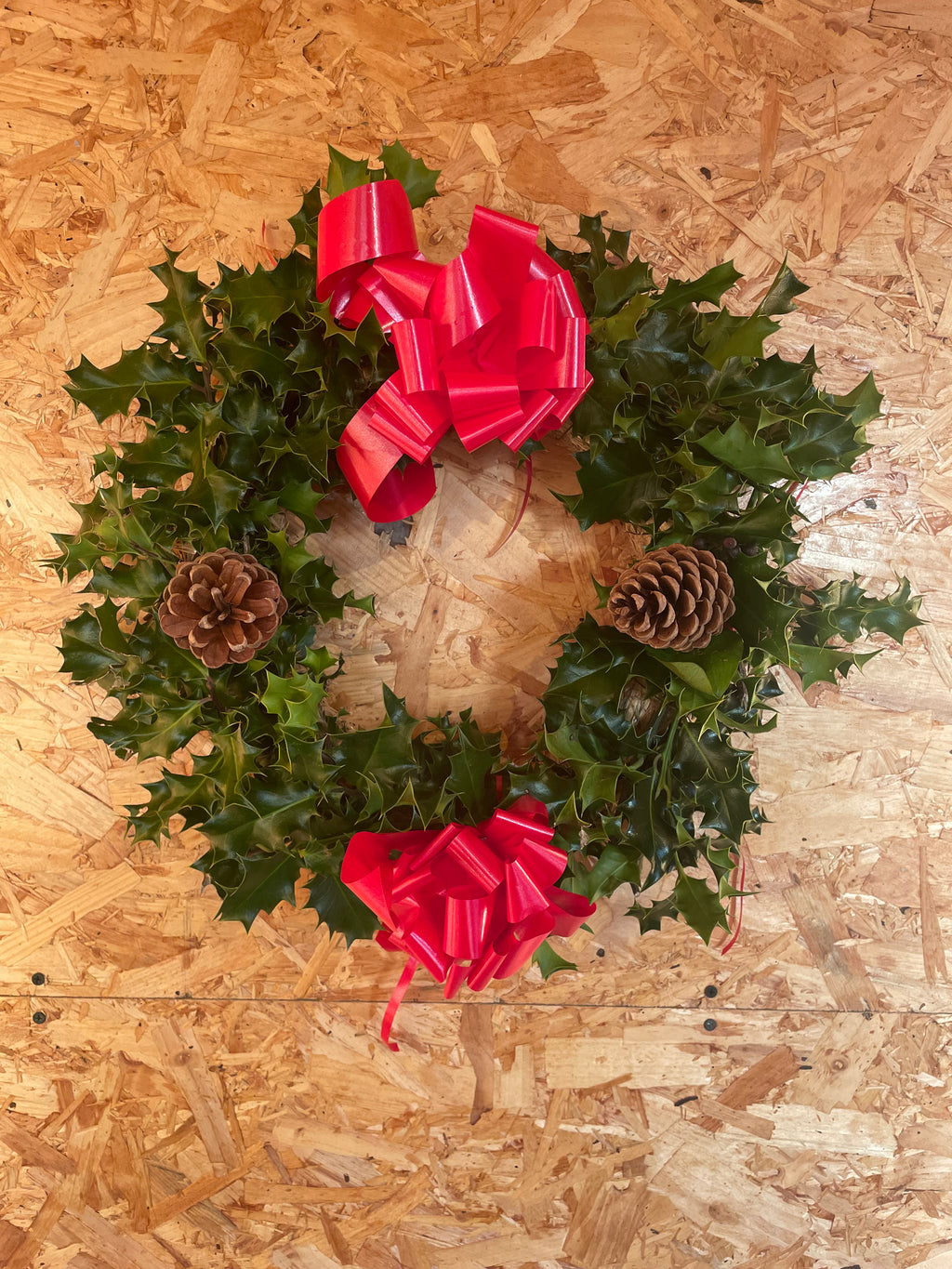 30cm Holly wreath decorated with pine cones and ribbons, available for delivery with your Christmas tree order from The Real Christmas Tree People.