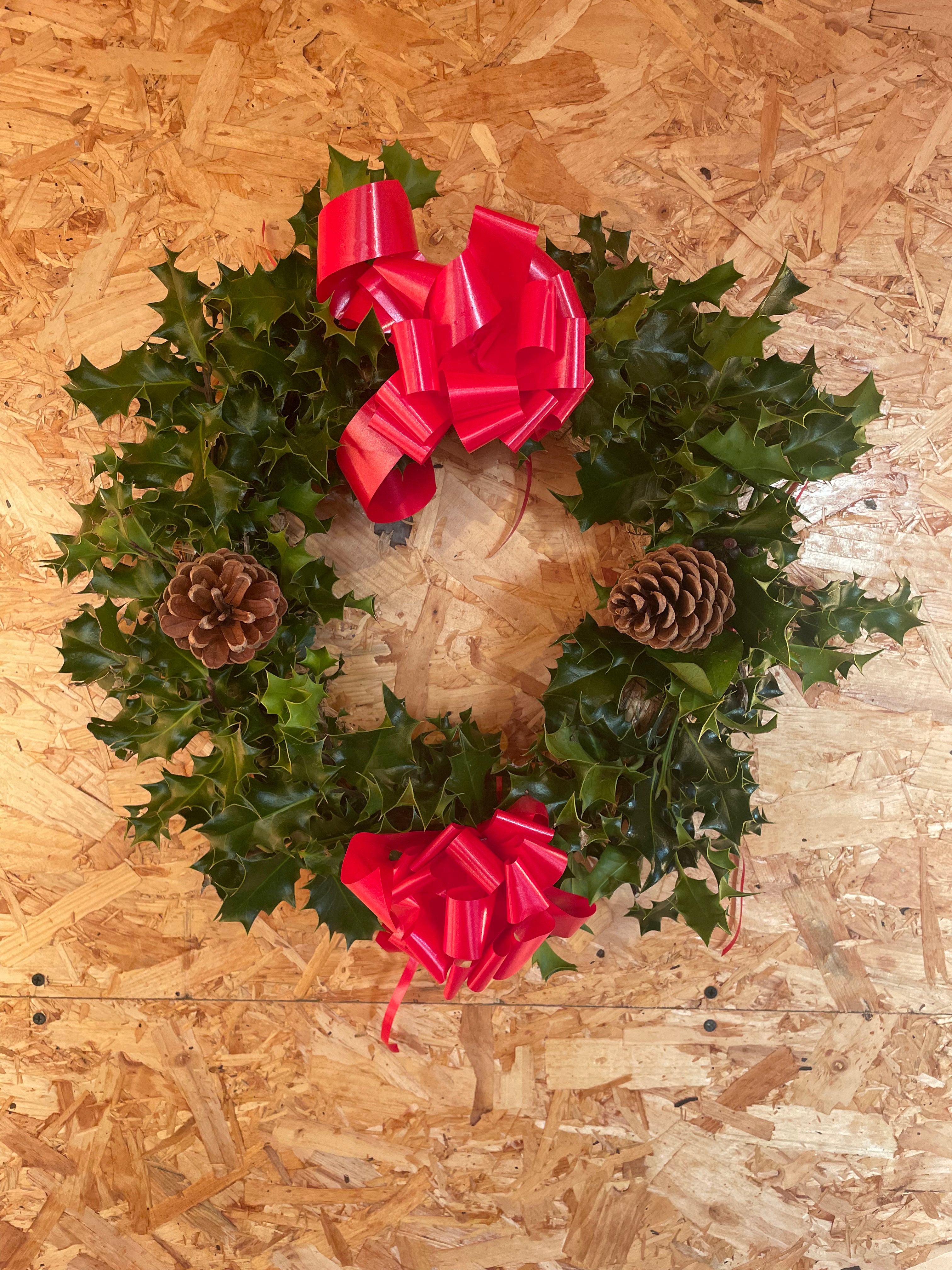 30cm Holly wreath decorated with pine cones and ribbons, available for delivery with your Christmas tree order from The Real Christmas Tree People.